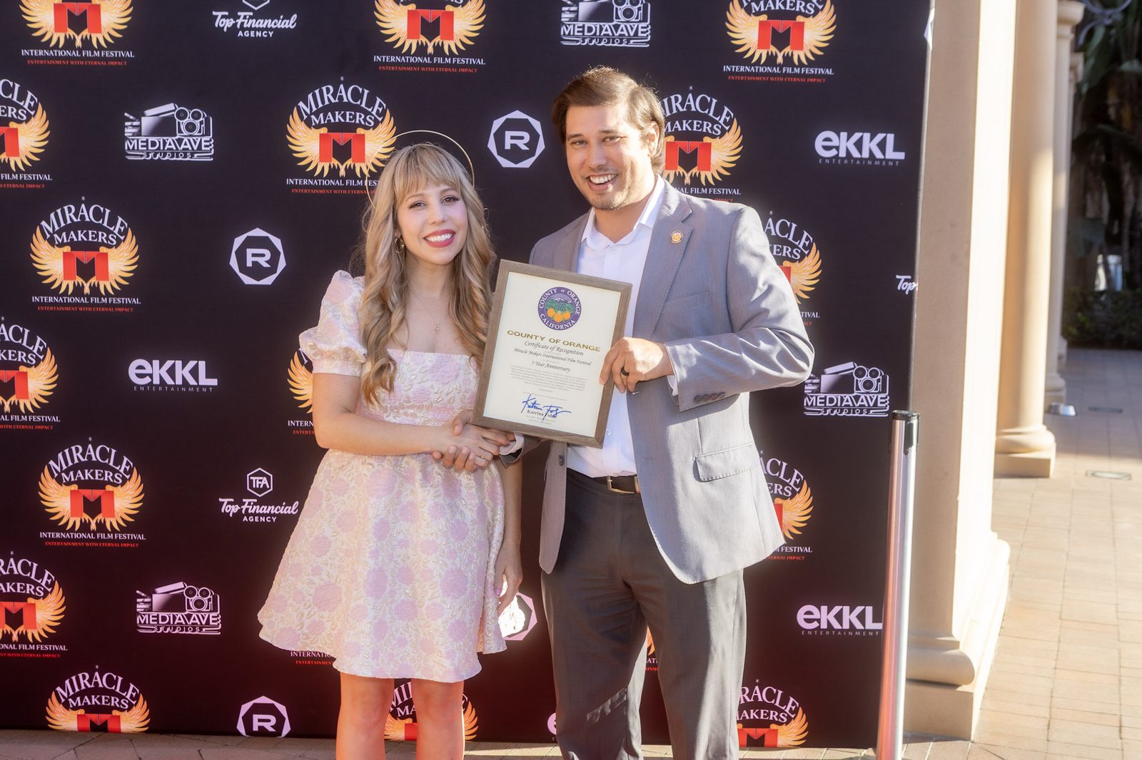 A framed presentation handed over on the red carpet in front of the festival backdrop